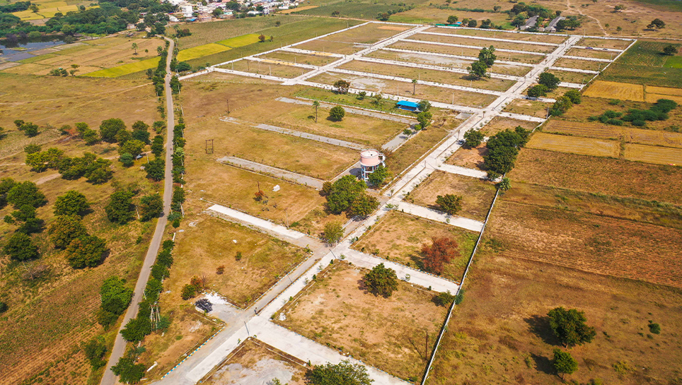 An aerial view of a rural area with houses and fields, showcasing the serene beauty of countryside living. OPEN PLOTS FOR SALE AT BAHUPETA